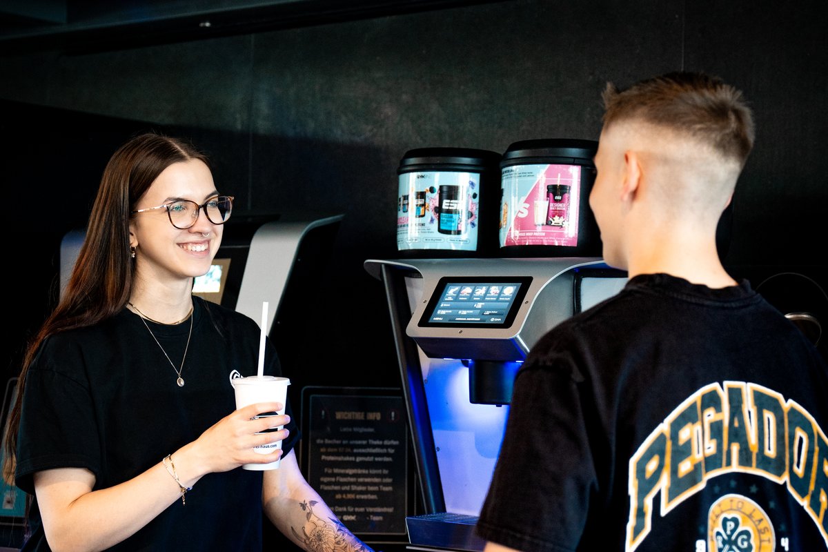 Zwei Mitglieder an der Shake-Bar mit JetMix Eiweißshake-Station im GymOne 24/7 Bitburg